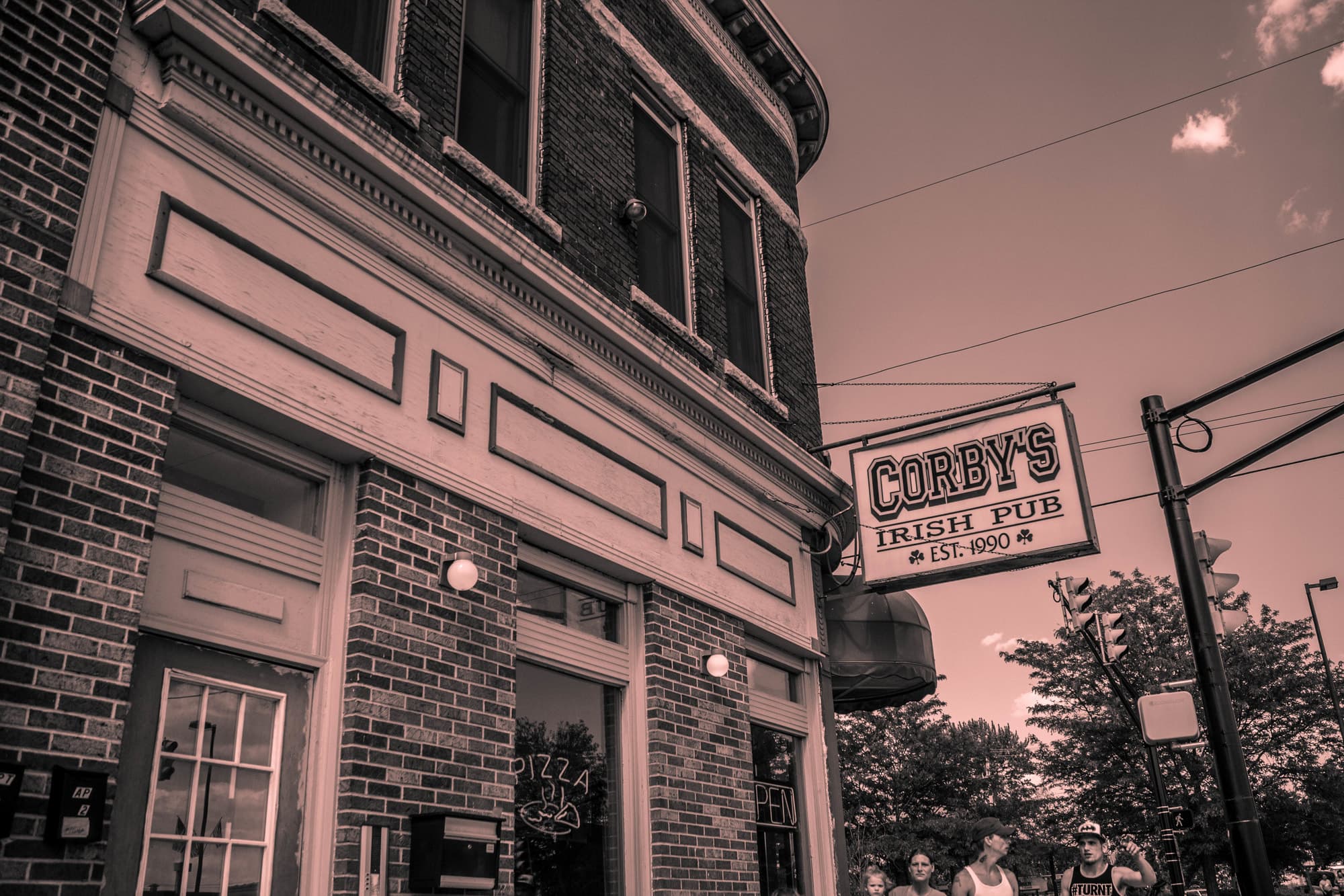 The Corby's Irish Pub hanging sign on the brick corner at LaSalle Avenue